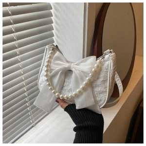 Detail of white pleated bag with large silk bow and decorative pearl handle