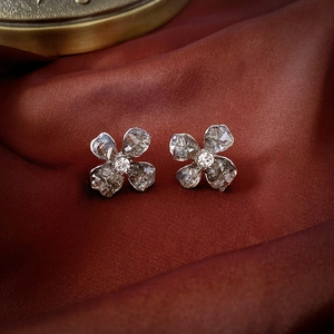 Detailed macro view of crystal flower earrings on luxury reddish-brown silk fabric
