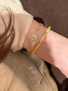 Detailed view of 18K gold plated celestial star bracelet and brushed metal bangle on wrist