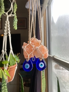Detail of hand-woven wall hanging with pink salt stones and blue evil eye glass beads