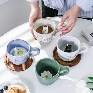 Close-up of ceramic mugs with 3D animal and floral designs inside the cups