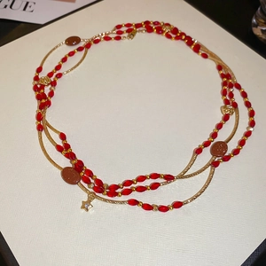 Close-up of layered beaded necklace with red resin beads and gold star pendant