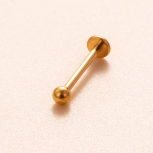 Macro view of a polished golden titanium labret stud with a ball top and flat disk base