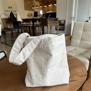 Detail of white canvas tote bag with colorful specks and durable woven texture