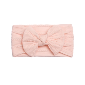 Detailed texture of baby nylon headband with large light pink twisted knit bow