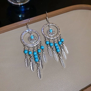 Detail of silver eagle earrings with turquoise beads and ethnic feather tassels