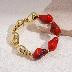 Gros plan de perles dorées irrégulières et pierres en résine rouge d'un bracelet