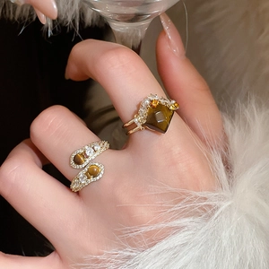 Close-up of golden snake ring with tiger eye stone and crystals on model hand