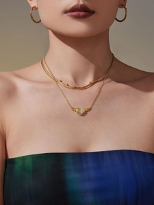 Detailansicht der mehrlagigen Goldkette mit Herzflügeln und gedrehten Creolen an Model