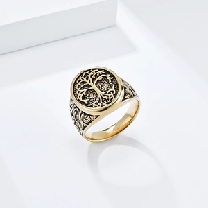 Macro view of men's gold and black stainless steel ring with Tree of Life engraving