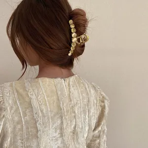 Detailed back view of a large gold alloy hair claw clip with cat eye stones in hair