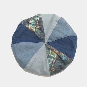 Detail view of the patchwork denim beret with vintage plaid textures and stitching