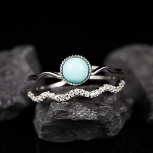 Detail of s925 silver rings with turquoise gemstone and pave zircons on dark rock