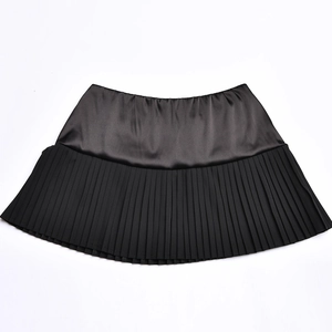 Detail of black mini skirt featuring a satin top panel and a pleated bottom design