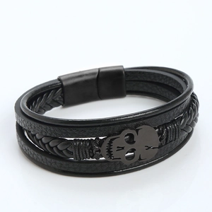 Detail of multi-layer black braided leather bracelet with metal skull and magnetic clasp