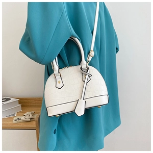 Macro detail of white crocodile pattern shell bag with golden metal hardware and strap