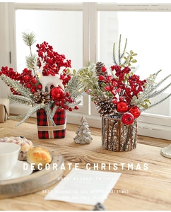 Close-up of Christmas arrangement with red berries, white deer, and pine cones on wood base