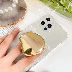 Close-up of golden irregular pebble-shaped foldable phone grip on white lace case