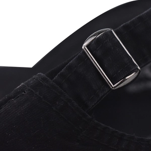 Détail de la boucle métallique et de la sangle en toile noire de la casquette