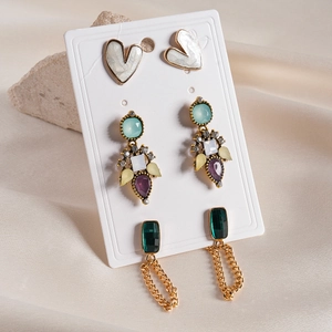 Détail de trois paires de boucles d'oreilles dorées avec cœurs et pierres colorées