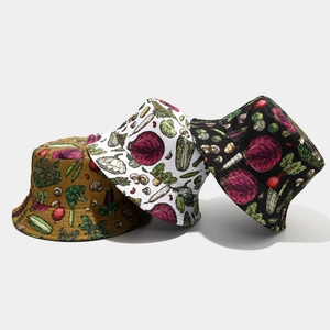 Detail of three bucket hats in mustard, white, and black with hand-drawn vegetable patterns