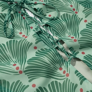 Close-up of green chiffon dress with leaf print and adjustable waist tie detail