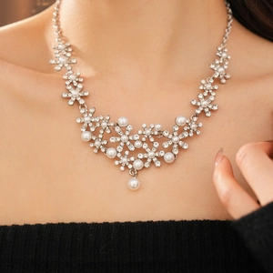 Detail view of a luxury floral necklace with diamonds and pearls worn by a model