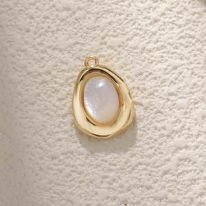 Irregular gold-plated copper pendant with oval white mother of pearl inlay on stone surface