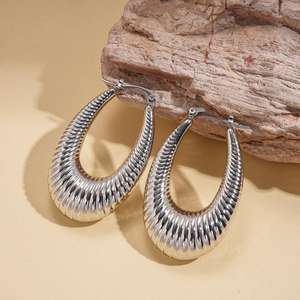 Macro shot of large silver hoop earrings with ribbed texture on organic stone surface