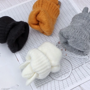 Flat lay of soft knitted winter gloves in black, orange, grey and white on wooden background