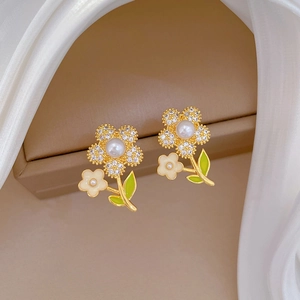 Detail of floral earring with white pearl center, rhinestones and green enamel leaf