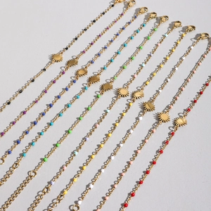 Golden sun charm bracelets featuring colorful beads and lobster clasp on grey surface