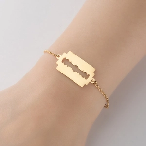 Minimalist gold razor blade pendant bracelet with polished cross chain on wrist