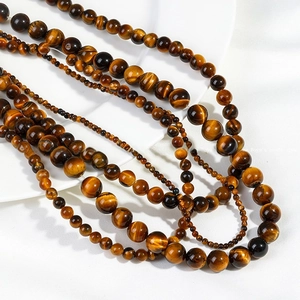 Close-up of natural yellow tiger eye faceted beads in various sizes on a white plate