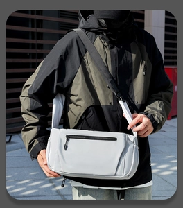 Outdoor shot of light gray waterproof crossbody bag worn with a techwear jacket