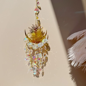 Close-up of golden sun-moon crystal suncatcher casting rainbow light on a plain wall