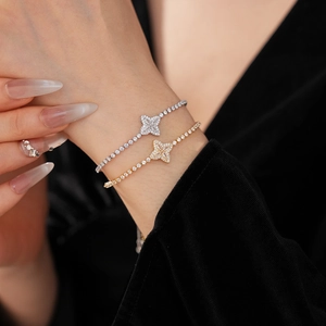 Detailed view of silver and gold adjustable bracelets with zircon clover flowers