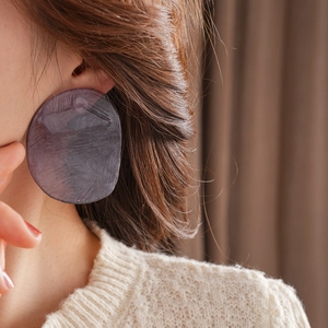 Close-up of stylish purple resin earrings with textured finish worn by a model