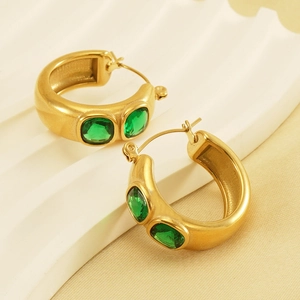Detailed view of matte 18K gold plated C-hoop earrings with emerald zircon stones