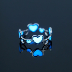 Close-up of heart stainless steel ring glowing blue in dark environment