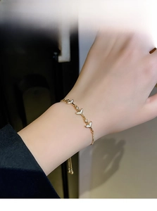 Detailed macro view of gold fish tail pendants with zircon stones on a delicate pearl bracelet