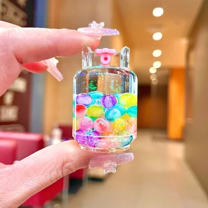 Macro view of a mini gas tank keychain with colorful flowing beads and liquid sand