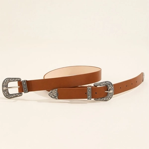 Close-up of vintage Western belt with dual engraved silver buckles and brown leather texture