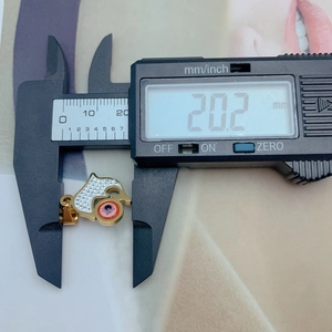 Macro view showing a golden Hamsa pendant measuring 20.2 mm with a red evil eye