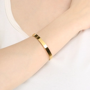 Minimalist 18K gold plated stainless steel bangle bracelet on model's wrist