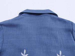 Detail of white leaf embroidery on back shoulder of blue lace splice blazer