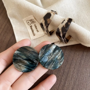 Gros plan de boucles d'oreilles géométriques en acrylique avec motifs écaillés et marbre