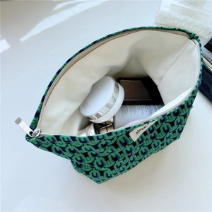 Macro detail of green printed cotton makeup bag with white lining and silver metal zipper
