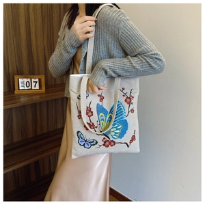 Lifestyle view of canvas tote bag with blue butterfly and red floral print on shoulder