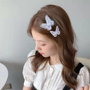 Detail of two white lace butterfly hair clips in different sizes on model's hair
